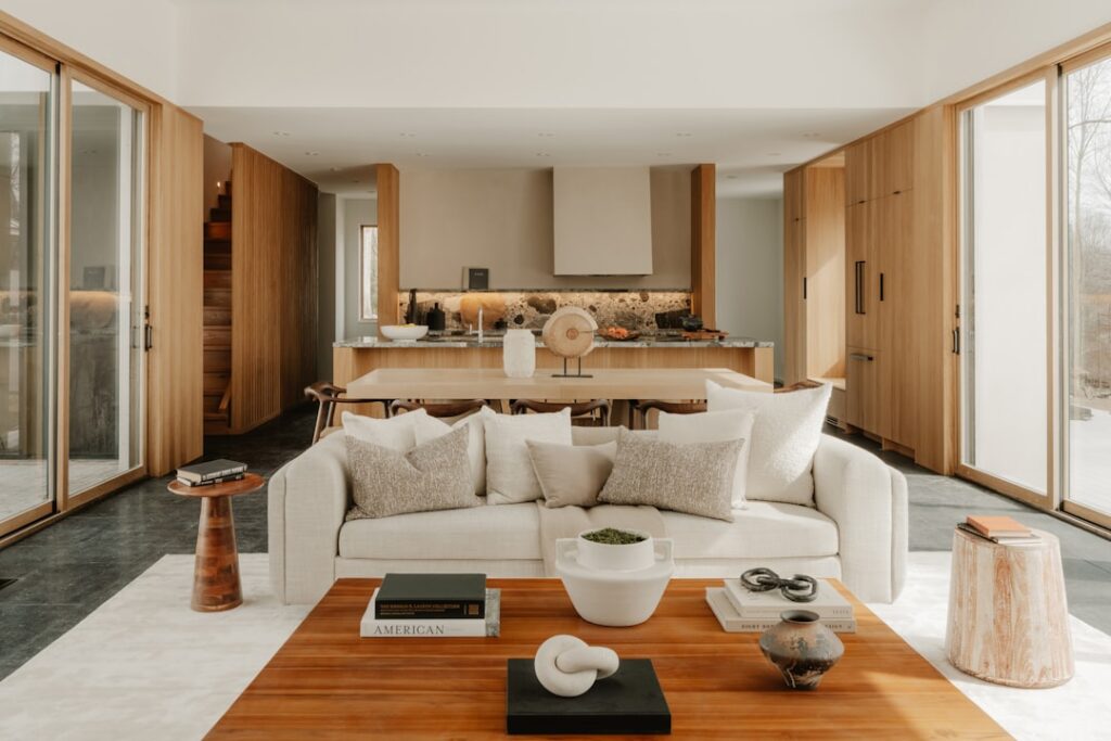 A bright, spacious home interior with a connected kitchen, dining, and living area and large windows letting in natural light.