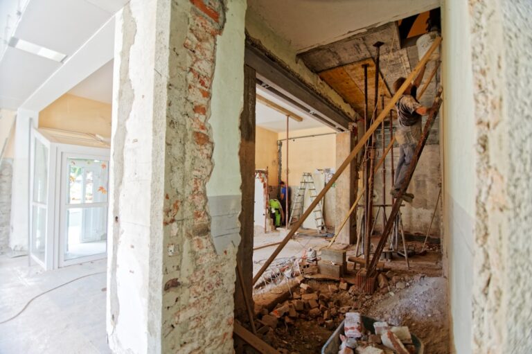 A residential room with partially removed walls and construction materials showing a space being remodeled.