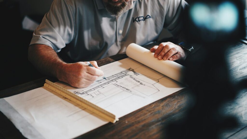 Homeowner reviewing residential construction plans beside a framed addition and permit documents.